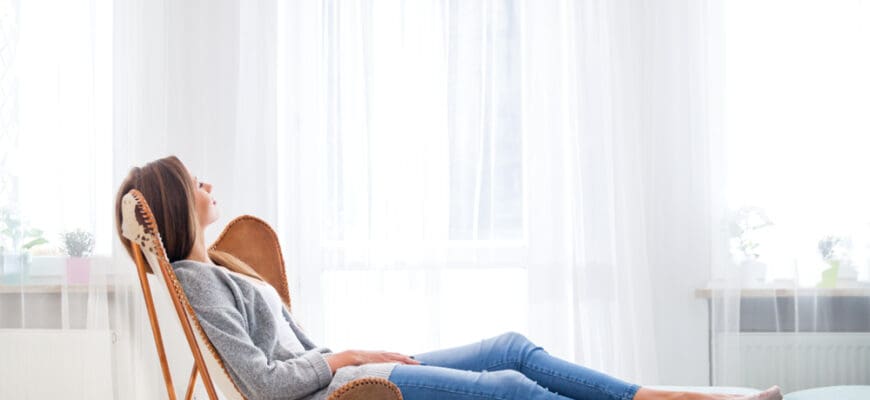 Young,Woman,At,Home,Sitting,On,Modern,Chair,Near,Window