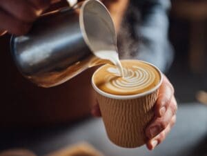 Close-up,Of,A,Barista,Pouring,Steamed,Milk,Into,A,Paper