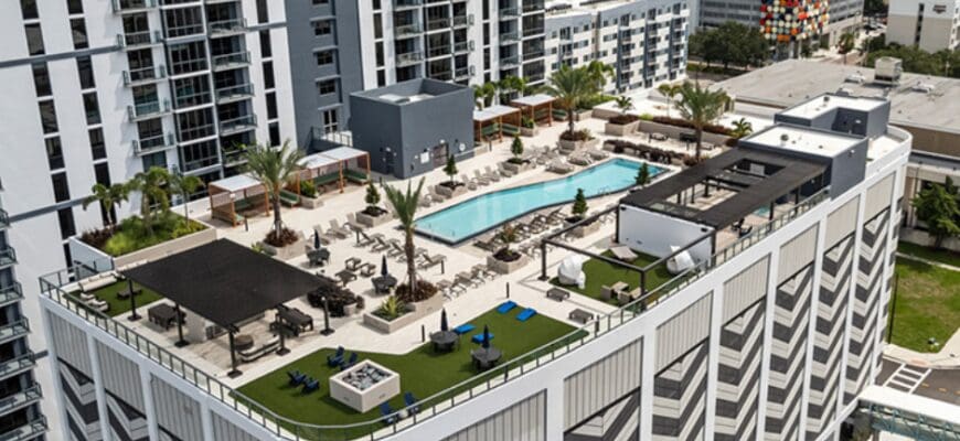An aerial view of the rooftop at AER Tampa apartments featuring a resort-style pool and lounge areas