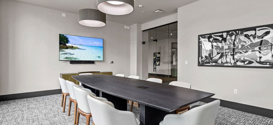 Co-Working lounge at AER Tampa with a conference table, chairs, overhead lighting, and a large TV screen